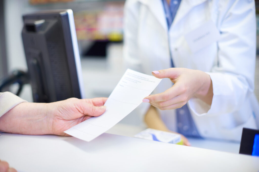 Pessoa segurando receita médica e formulário da Anvisa para importar medicamentos legalmente